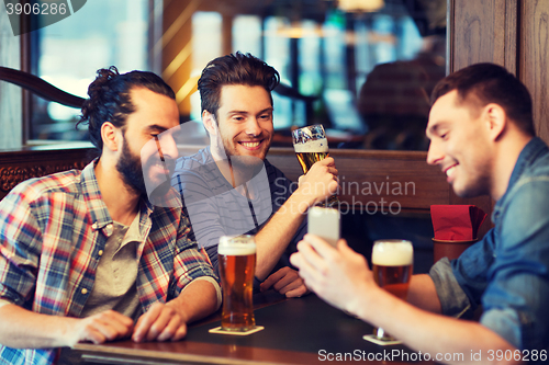 Image of male friends with smartphone drinking beer at bar