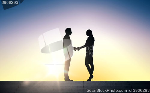 Image of business partners silhouettes shaking hands