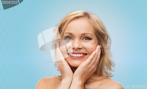 Image of smiling woman with bare shoulders touching face