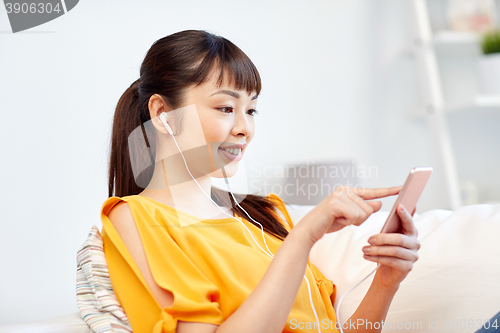 Image of happy asian woman with smartphone and earphones