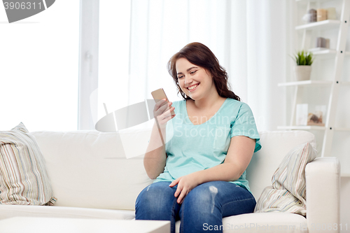 Image of happy plus size woman with smartphone at home