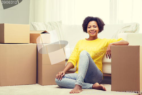 Image of happy african woman with cardboard boxes at home