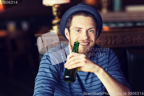 Image of happy young man drinking beer at bar or pub