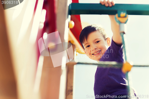 Image of happy little boy climbing on children playground