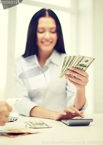 Image of close up of woman counting money with calculator