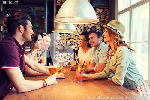 Image of happy friends with drinks talking at bar or pub