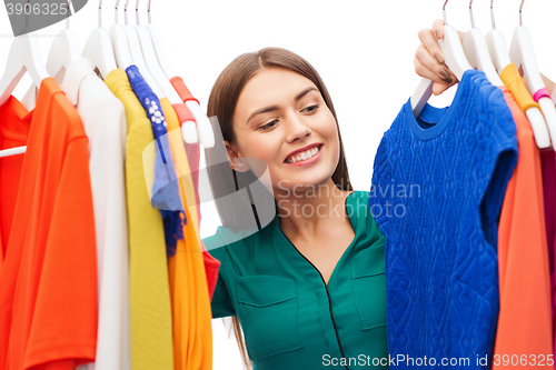 Image of happy woman choosing clothes at home wardrobe