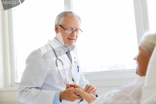 Image of doctor checking senior woman pulse at hospital