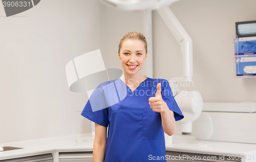 Image of happy female dentist showing thumbs up at clinic