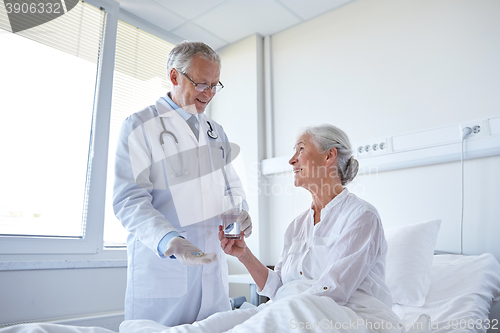 Image of doctor giving medicine to senior woman at hospital