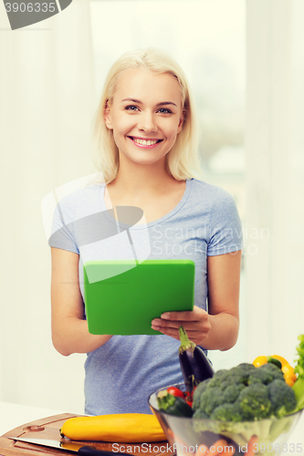 Image of smiling young woman with tablet pc cooking at home