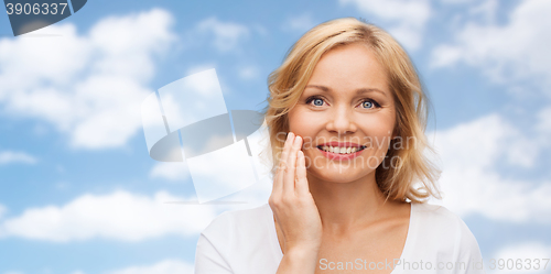 Image of smiling woman in white t-shirt touching her face