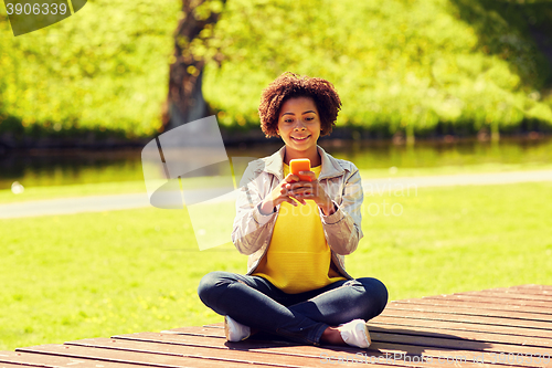 Image of happy african young woman messaging on smartphone