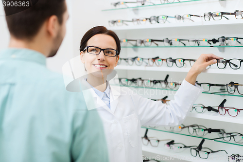 Image of optician showing glasses to man at optics store