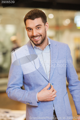 Image of happy young man in jacket at clothing store