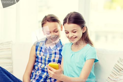 Image of happy girls with smartphone sitting on sofa