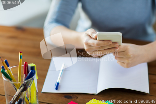 Image of close up of student with smartphone and notebook