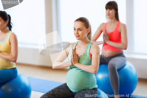 Image of happy pregnant women exercising on fitball in gym