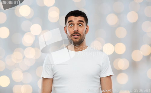 Image of scared man in white t-shirt over lights background