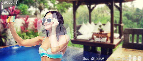 Image of woman in swimsuit taking selfie with smatphone