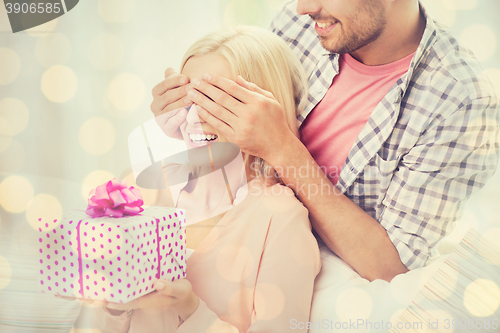 Image of happy man giving woman gift box at home