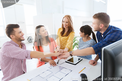 Image of creative team holding hands together  at office