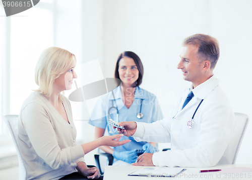 Image of doctor giving tablets to patient in hospital