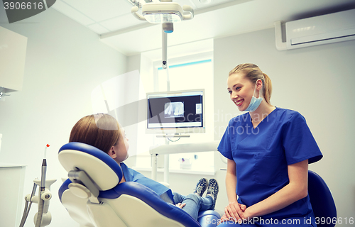 Image of happy female dentist with patient girl at clinic