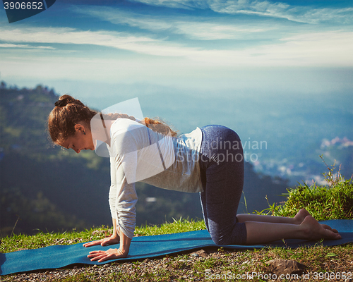 Image of Sporty fit woman practices yoga asana bitilasana outdoors