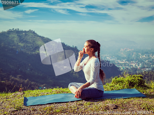 Image of Woman practices pranayama in lotus pose outdoors