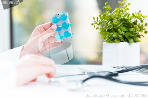 Image of Hand of female medicine doctor holding tablet blister closeup. 