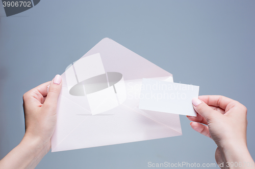 Image of The female hands with envelope against the gray background