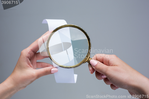 Image of The female hands with  empty transaction paper or paper check and magnifier