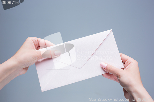 Image of The female hands with envelope against the gray background