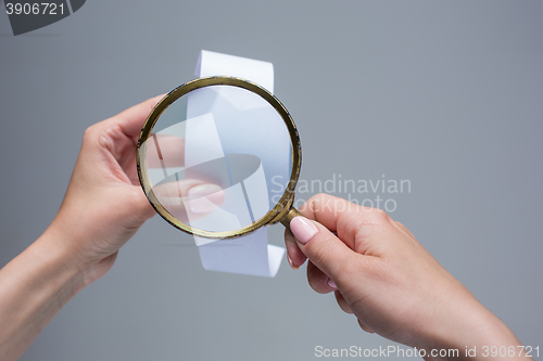 Image of The female hands with  empty transaction paper or paper check and magnifier