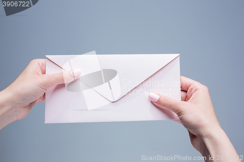 Image of The female hands with envelope against the gray background