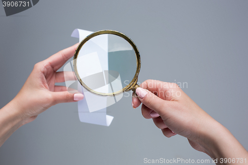 Image of The female hands with  empty transaction paper or paper check and magnifier