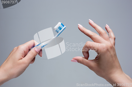 Image of Toothbrush in woman\'s hands on gray