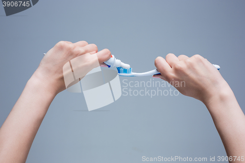 Image of Toothbrush in woman\'s hands on gray