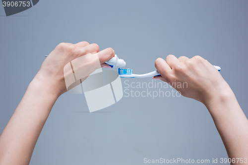 Image of Toothbrush in woman\'s hands on gray