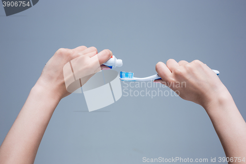 Image of Toothbrush in woman\'s hands on gray