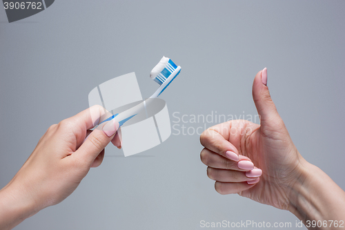 Image of Toothbrush in woman\'s hands on gray
