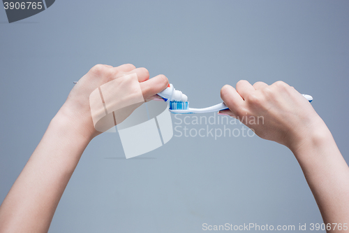 Image of Toothbrush in woman\'s hands on gray