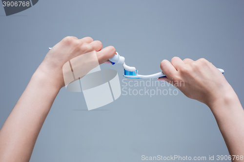 Image of Toothbrush in woman\'s hands on gray