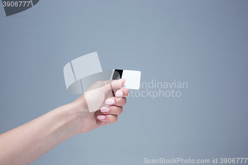 Image of The card in a female hand is on a gray background