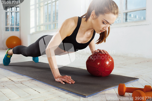 Image of Beautiful slim brunette doing some gymnastics at the gym