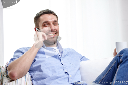 Image of smiling man with smartphone at home