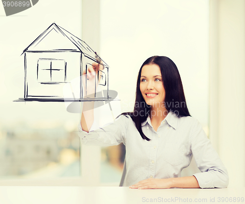 Image of smiling woman drawing house on virtual screen