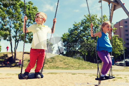 Image of two happy kids swinging on swing at playground