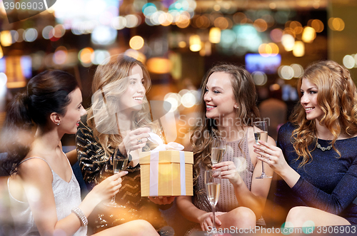 Image of happy women with champagne and gift at night club